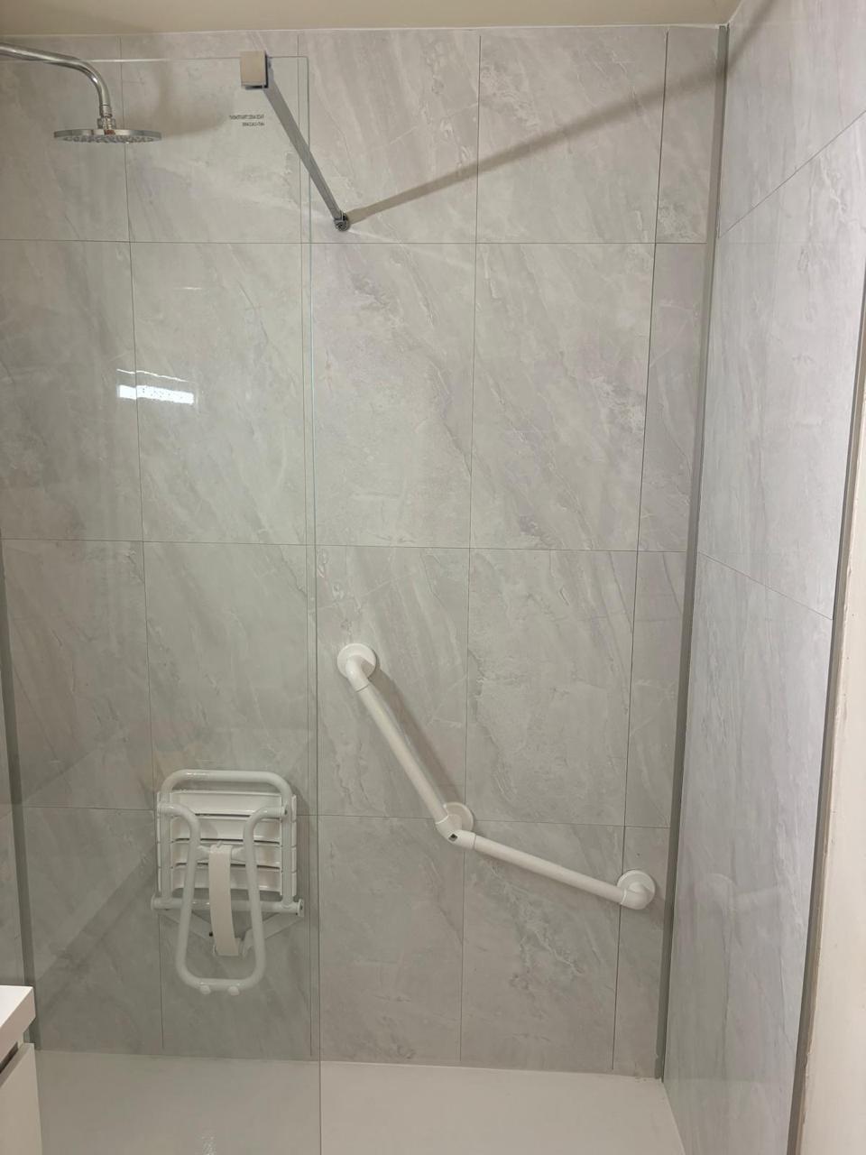 Détail réel : barre d'appui et siège de douche installés